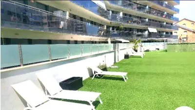 a lawn with lounge chairs on the side of a building at Ideal for families on the beach in Barcelona with a pool in Badalona