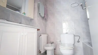 a white bathroom with a toilet and a sink at Cosy flat in pretty seaside town in Sitges