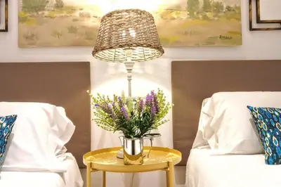 a vase of flowers on a table next to two beds at La Rambla spacious 3BR monthly rental - Parsifal in Barcelona