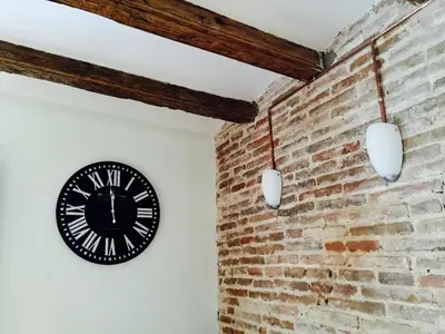 a black clock on a brick wall with two lights at Apartments Barcelona Sagrada in Barcelona