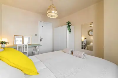 a bedroom with a large white bed with yellow pillows at Atlantida House Self Check-in in Hospitalet de Llobregat