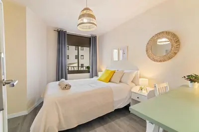 a bedroom with a white bed and a table at Atlantida House Self Check-in in Hospitalet de Llobregat