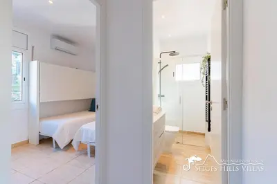 a white bedroom with a bed and a bathroom at Sunny Villa Moments near Sitges in Olivella