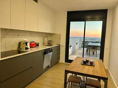 a kitchen with a table and a view of a balcony at Les Flors de Cunit Villa Edelweiss in Cunit