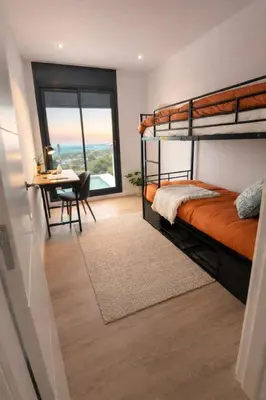 a bedroom with bunk beds and a table and a desk at Les Flors de Cunit Villa Edelweiss in Cunit