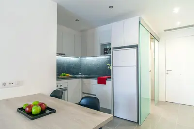 a kitchen with white cabinets and a table with fruit on a plate at Aparteasy - Deluxe Family Apartments with Pool in Barcelona