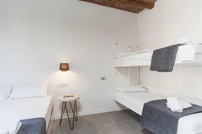 a white room with two beds and a table at Aparteasy - Deluxe Family Apartments with Pool in Barcelona