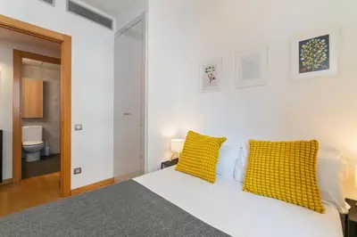 a white bedroom with a bed with yellow pillows at Modern Spacious 3-Bedroom Apt with Pool near Beach in Barcelona