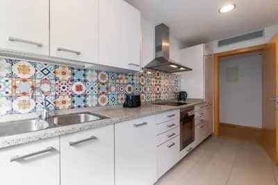 a kitchen with white cabinets and a tile wall at Modern Spacious 3-Bedroom Apt with Pool near Beach in Barcelona