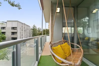 a hanging chair on a balcony with yellow pillows at Modern Spacious 3-Bedroom Apt with Pool near Beach in Barcelona