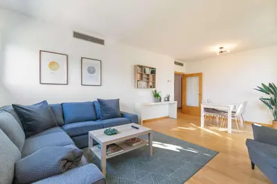 a living room with a blue couch and a table at Modern Spacious 3-Bedroom Apt with Pool near Beach in Barcelona
