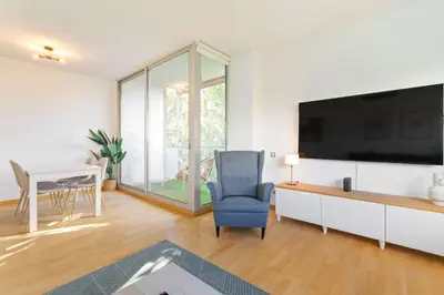 a living room with a tv and a chair and a table at Modern Spacious 3-Bedroom Apt with Pool near Beach in Barcelona