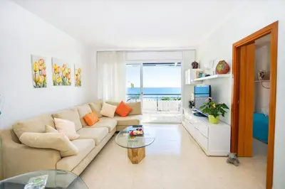 a living room with a couch and a glass table at Winahost El balcón al mar de Cubelles in Cubelles
