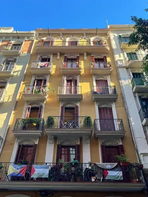 a tall yellow building with balconies and windows at 