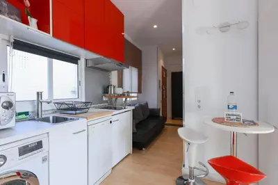 a kitchen with red cabinets and a sink and a table at ApartEasy - Lovely Atic in Barcelona in Barcelona