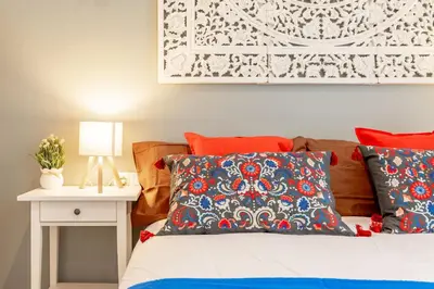 a bedroom with a bed with red and blue pillows at Studio Premium en Sants a 15' Bcn Centro y Fira Bcn in Barcelona