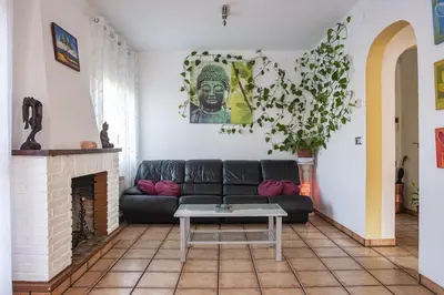 a living room with a black couch and a fireplace at Cal Sopas in Collbató