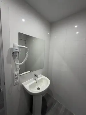 a white bathroom with a sink and a mirror at Hostel Hock Residences in Hospitalet de Llobregat