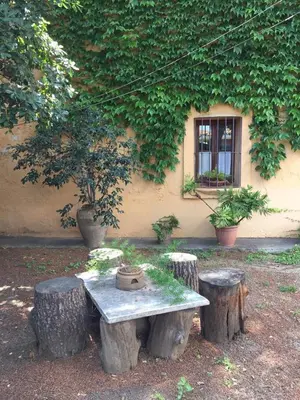 a table with tree stump stools in front of a building at Casa de pueblo con jardín in Premiá de Mar