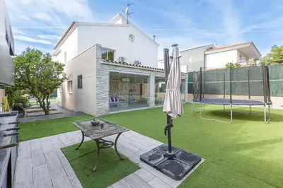 a patio with an umbrella and a table and a swing at Fantástica casa en alquiler con piscina en Vilanova i la Geltrú in Vilanova i la Geltrú