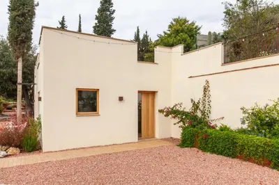 a white house with a door in a garden at Aldana accommodation in the middle of nature in Molins de Rei