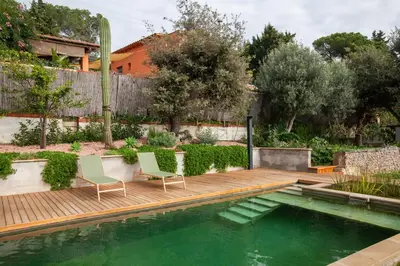 a swimming pool with two chairs and a wooden deck at Aldana accommodation in the middle of nature in Molins de Rei