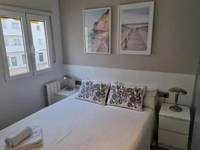 a bedroom with a white bed with two windows at Sitges Oasis in Sitges
