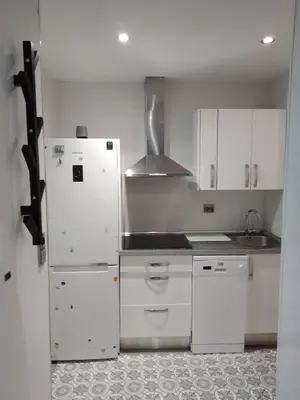 a kitchen with white cabinets and a white refrigerator at Sitges Oasis in Sitges