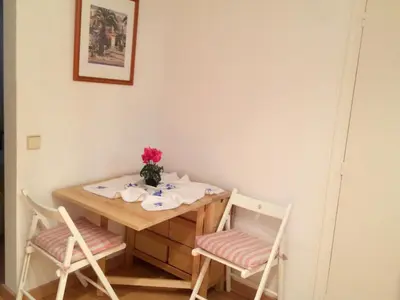 a table with two chairs and a vase of flowers at Apartaments Mare Nostrum in Sitges
