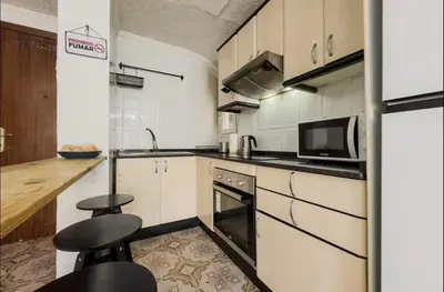 a kitchen with white cabinets and black appliances at Apartamento en Barcelona Pau sans in Hospitalet de Llobregat