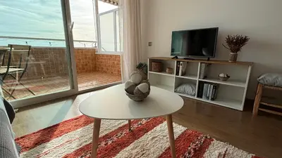 a living room with a table and a tv at Apartamento precioso en primera línea de mar in Les Botigues de Sitges