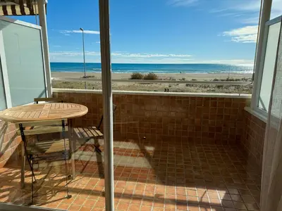 a balcony with a table and a view of the beach at Apartamento precioso en primera línea de mar in Les Botigues de Sitges