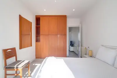 a bedroom with a white bed and a wooden cabinet at Guest Ready‑Bright & Stylish Flat with 3 Terraces in Barcelona