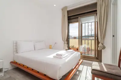 a bedroom with a large white bed and a window at Guest Ready‑Bright & Stylish Flat with 3 Terraces in Barcelona