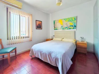 a bedroom with a bed and a chair and a window at Apartamento Canet de Mar Playa, Costa de Barcelona in Canet de Mar