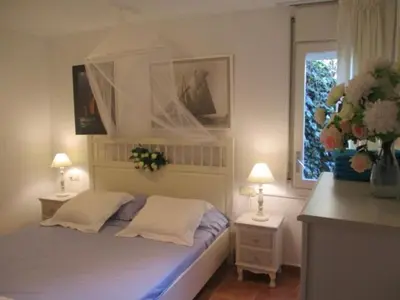 a bedroom with a bed with two tables and a window at Lovely little house with garden in Sant Vicenç de Montalt