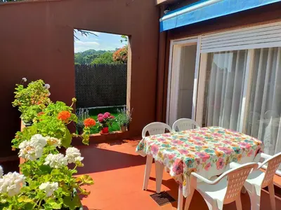 a table and chairs on a balcony with a table and flowers at Lovely little house with garden in Sant Vicenç de Montalt