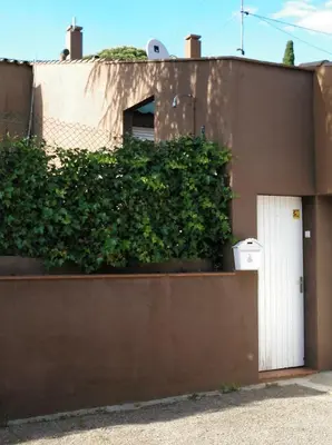 a building with a white door and a green hedge at Lovely little house with garden in Sant Vicenç de Montalt