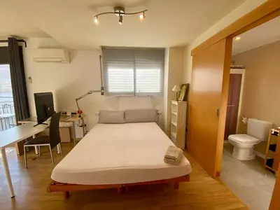 a bed in a room with a desk and a bed sidx sidx sidx at Loft muy soleado en Terrassa in Terrassa