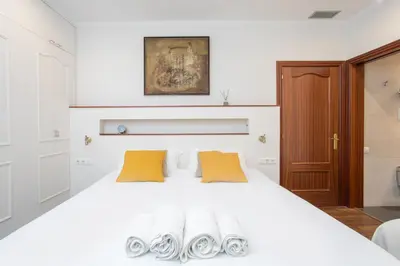 a bedroom with a white bed with two yellow pillows at Canela Homes BARCELONA MERCÈ in Barcelona