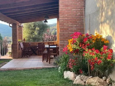 a patio with a table and chairs and flowers at Cal correu Hort - Xida in Collsuspina