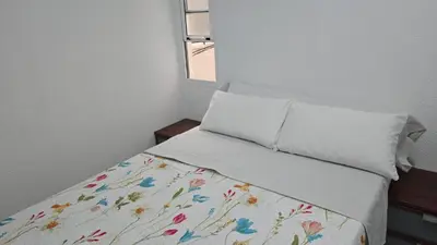 a bedroom with a bed with a floral bedspread and a window at A 10 de sagrada familia minutos caminando in Barcelona