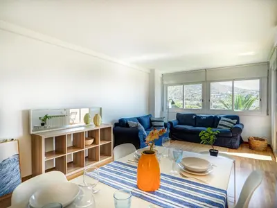 a living room with a table and a blue couch at Viva Palms by Hello Homes Sitges in Sitges