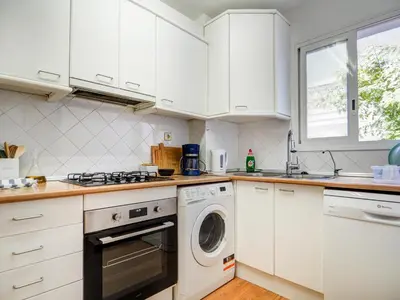 a kitchen with white cabinets and a washer and dryer at Viva Palms by Hello Homes Sitges in Sitges