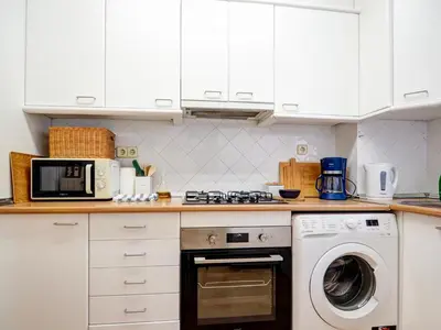 a kitchen with white cabinets and a washing machine at Viva Palms by Hello Homes Sitges in Sitges