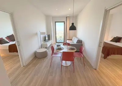 a white bedroom with a white bed and a desk at aparto Diagonal Suites in Esplugues de Llobregat