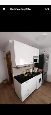 a kitchen with white cabinets and a black refrigerator at Studio B in Santa Coloma de Gramanet