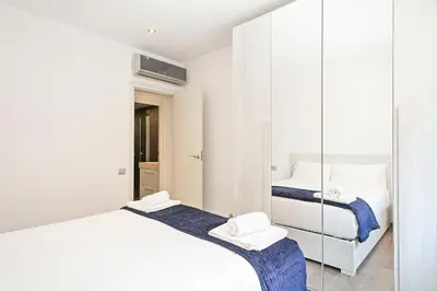 a white room with two beds and a mirror at Dialez Holidays - Sant Nicasi in Gavà