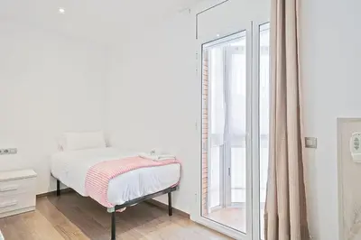 a bedroom with a bed and a large window at Dialez Holidays - Sant Nicasi in Gavà