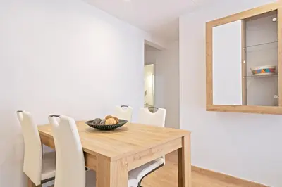 a dining room table with white chairs and a mirror at Dialez Holidays - Colomeres in Gavà